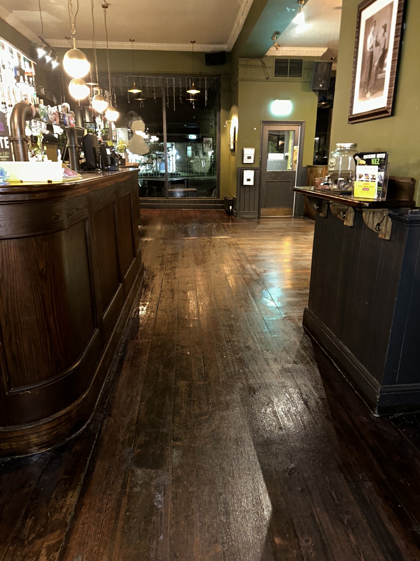 Before floor buffing — worn dark wood pub floor showing scuffs and dullness